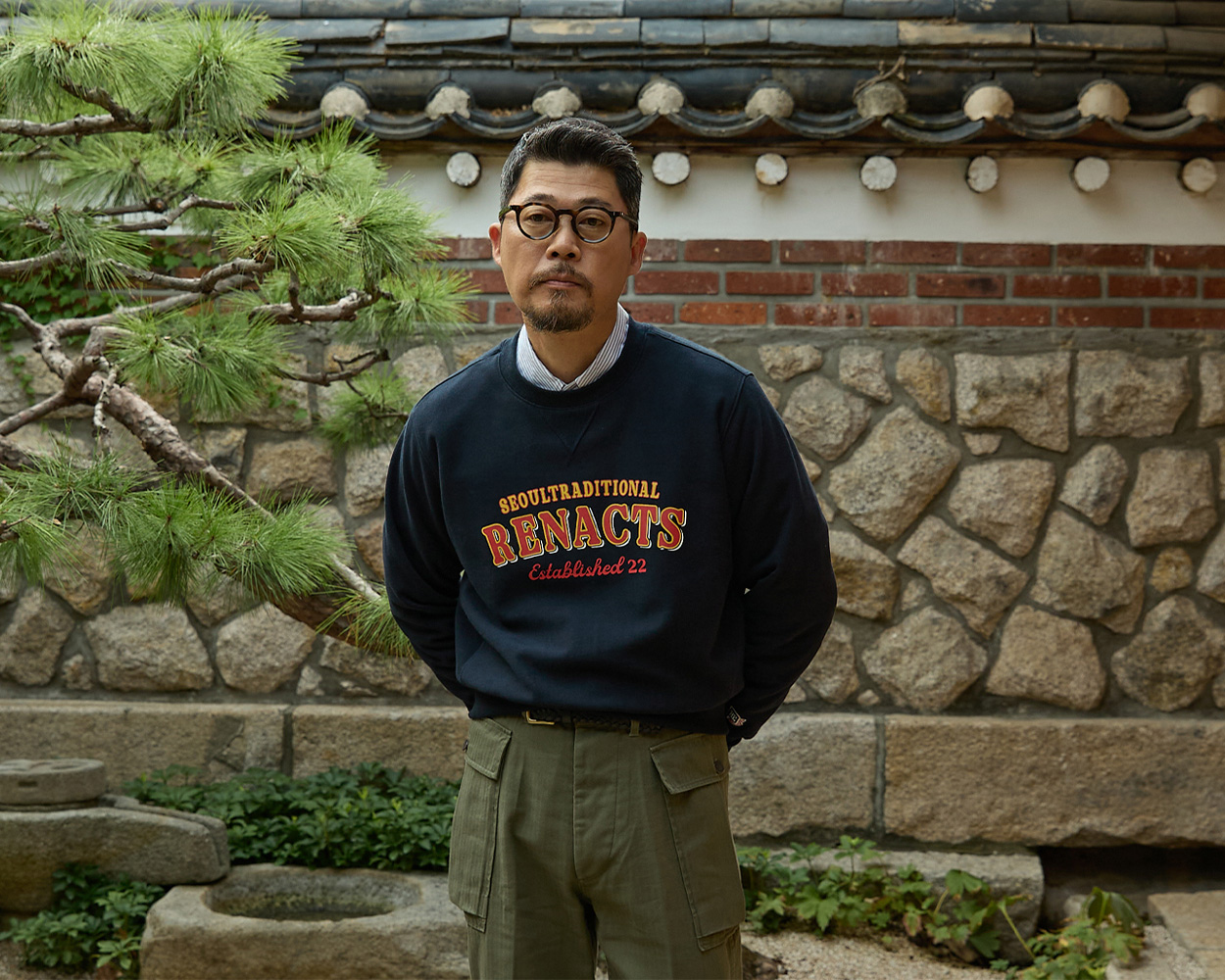 a man wears sweatshirt and olive pants