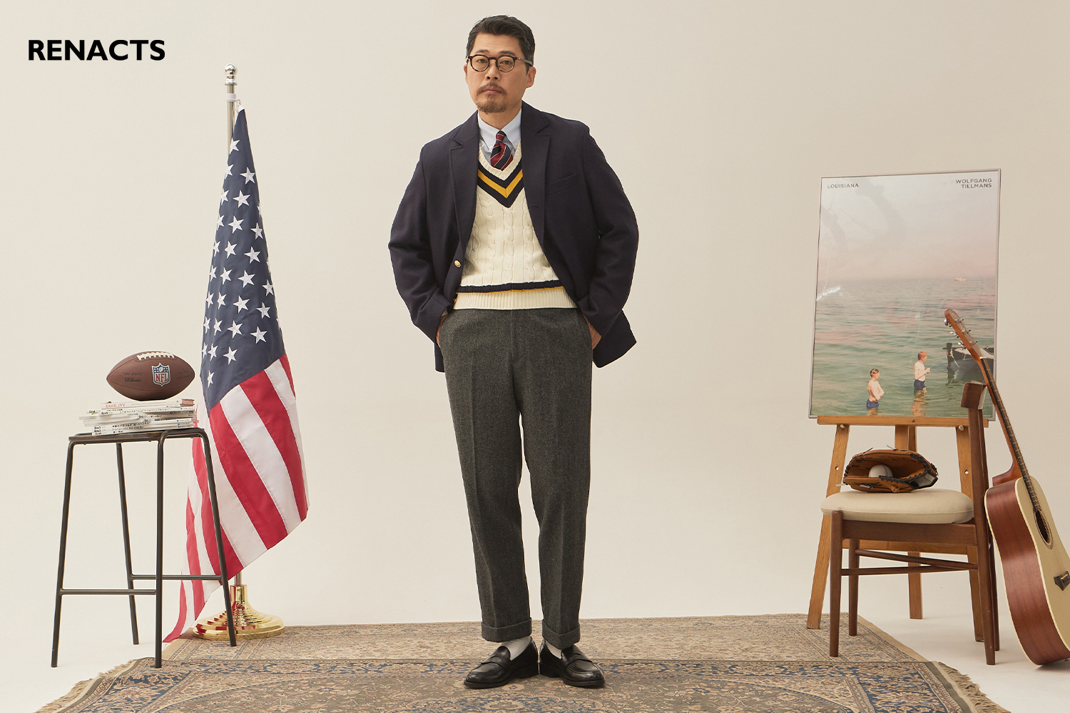 a man wears navy gold button blazer, cricket sweater, grey slacks and tie