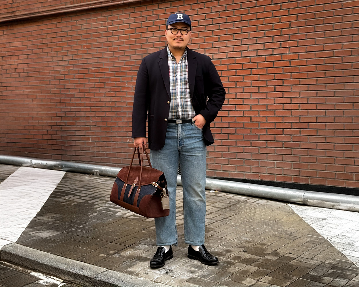 a man wears navy brass button blazer, check shirt and jeans