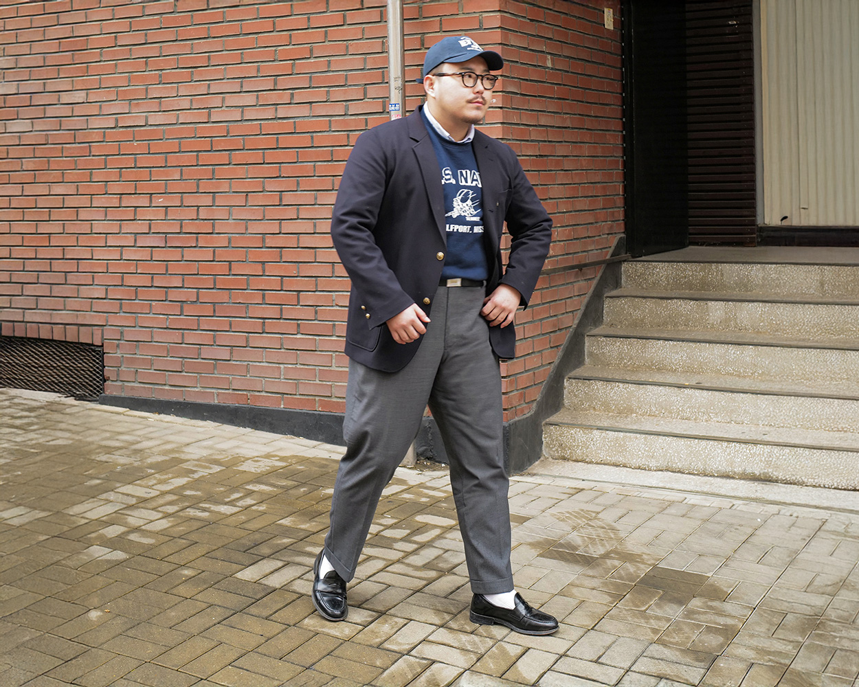 a man walking with his navy brass button blazer and grey trousers