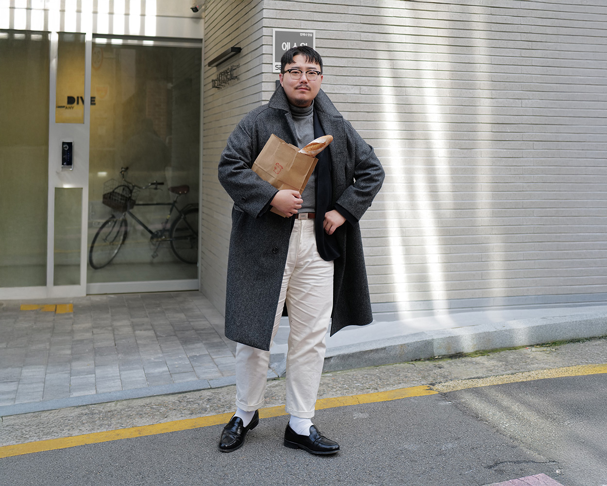 Balmacaan coat layered over a navy blazer with a grey turtleneck and ivory chinos for a smart winter American Casual outfit