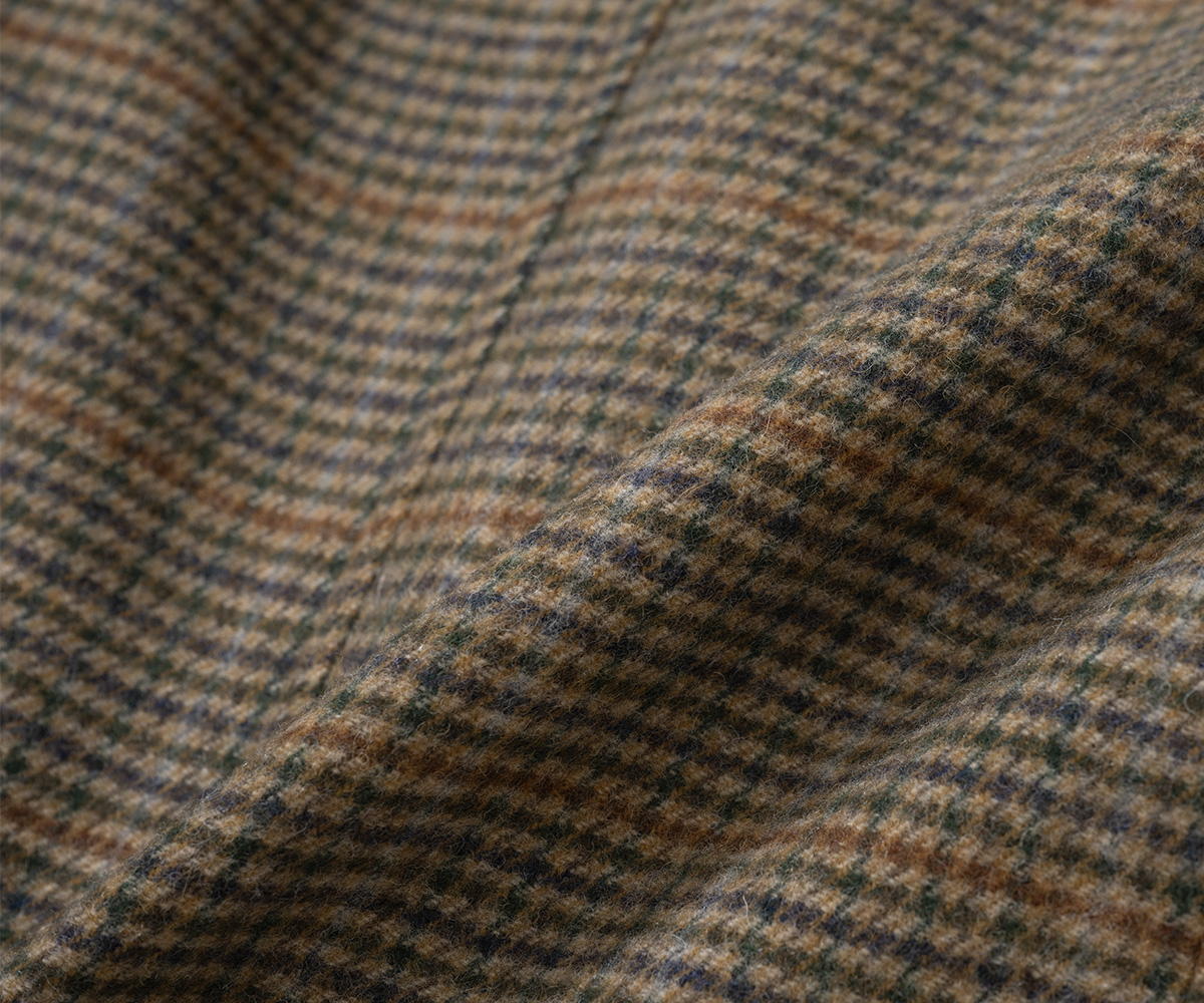 A close-up shot of luxurious jacket fabrics featuring herringbone and check patterns.