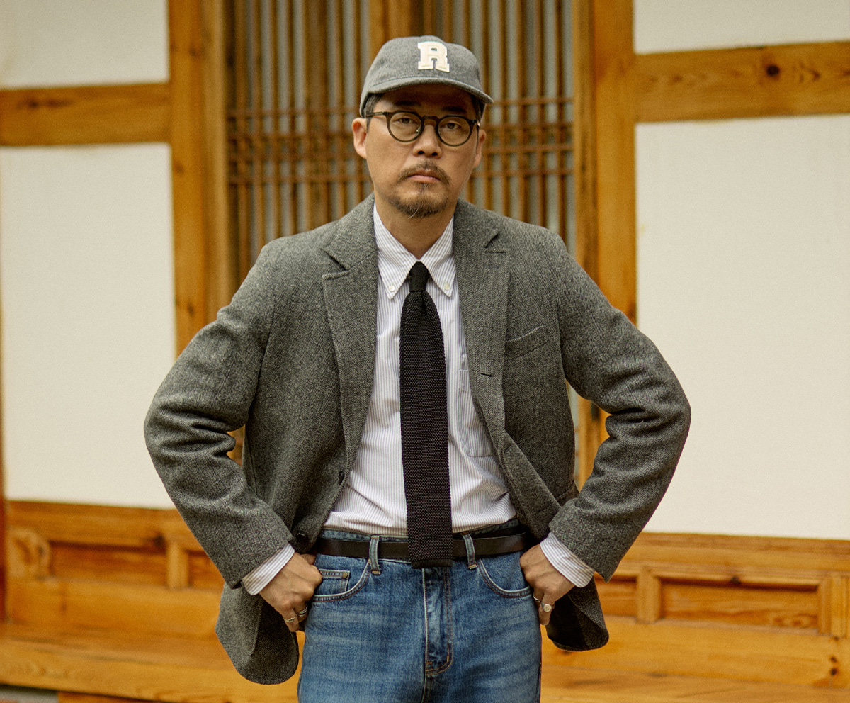 Atmospheric photo of a man in a sack jacket lost in thought in a classic study room.