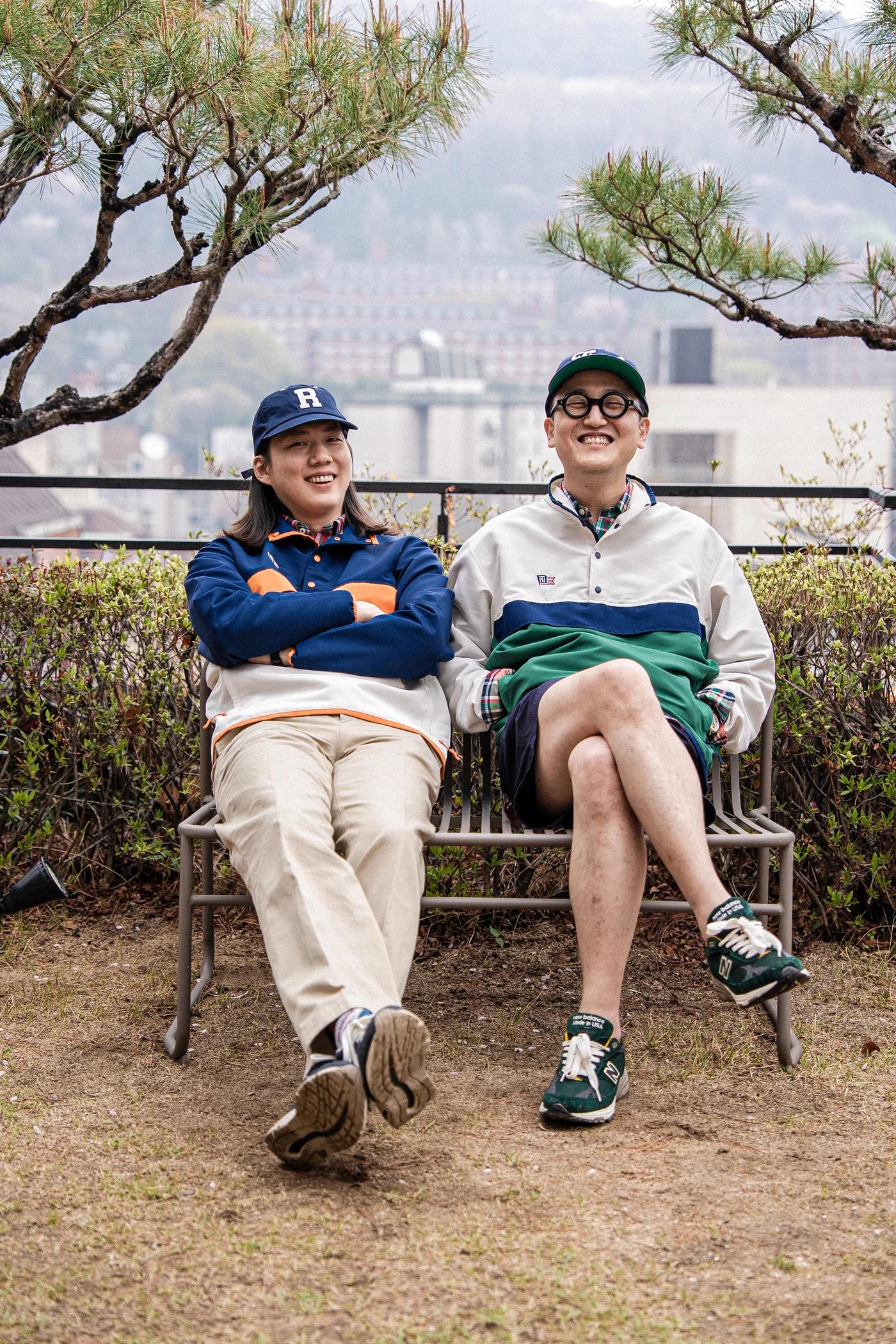 Anorak outfit men spring — couple on a Seoul bench in matching navy and green Renacts anoraks