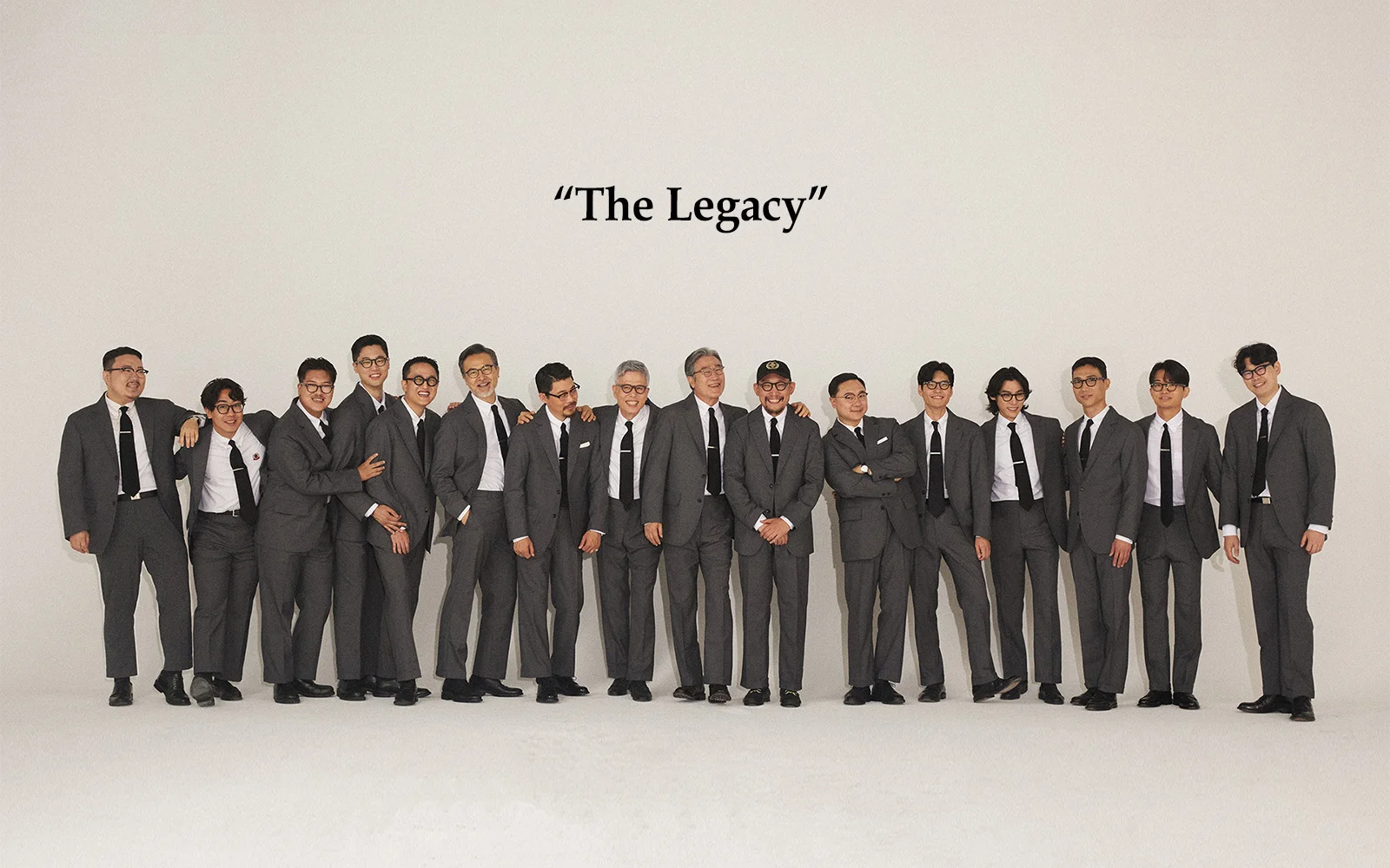 Brooks Brothers history in Seoul: 'The Legacy' editorial portrait — 16 Renacts team members standing in a row wearing grey sack suits with black ties, carrying the Number One Sack Suit silhouette into 2025