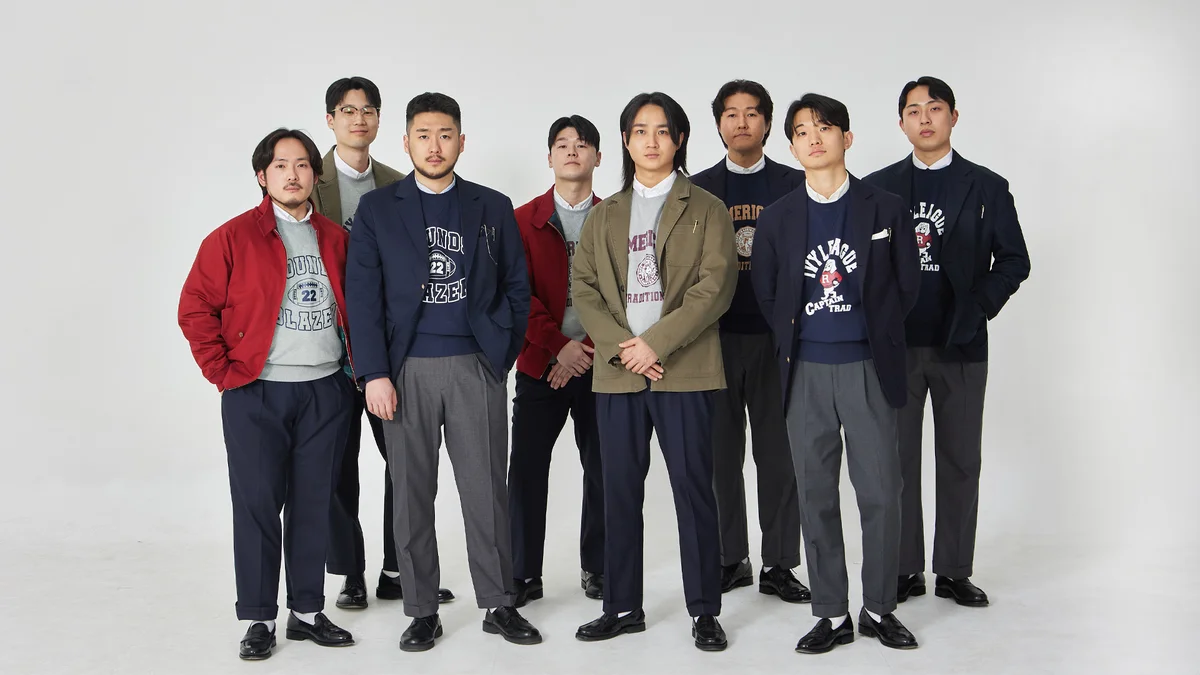 Seoul Heavy Ivy layering — crewneck sweater under anorak on a modern Seoul street, adapting Trad style for Korean winters