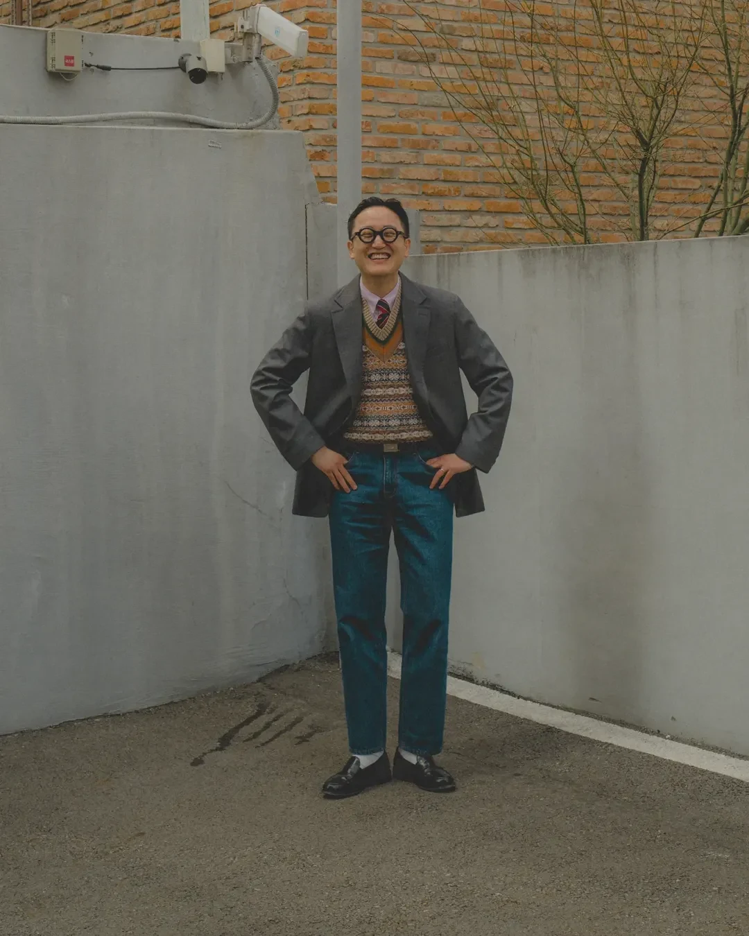 How to wear a Fair Isle vest with denim: charcoal grey blazer over Fair Isle vest, OCBD, regimental rep tie, dark denim, and black penny loafers