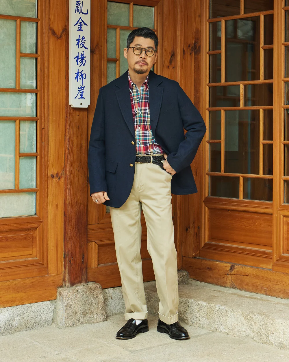 How to wear madras shirt — navy blazer over red madras with khaki chinos and black loafers at a hanok doorway