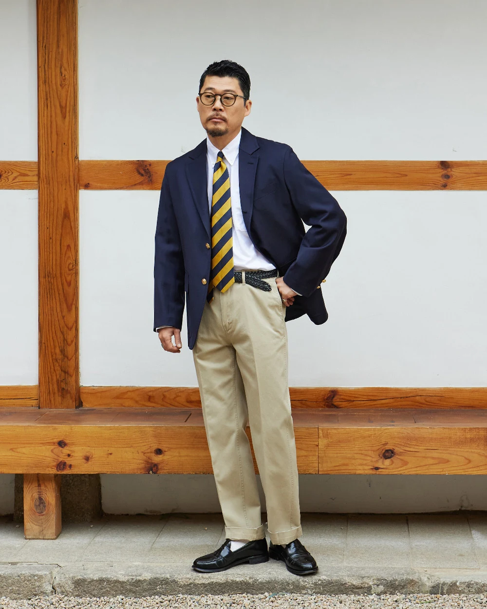 Navy gold-button blazer outfit — single-breasted blazer, white OCBD, regimental rep tie, light beige chinos, plaque belt, black penny loafers, lighter spring-summer preppy variant