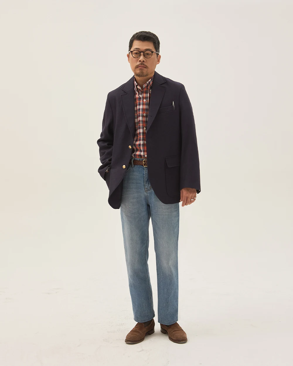 Navy gold-button blazer outfit — single-breasted blazer, plaid madras shirt, dark indigo denim trousers, plaque belt, brown suede penny loafers, madras and denim spring-summer casual