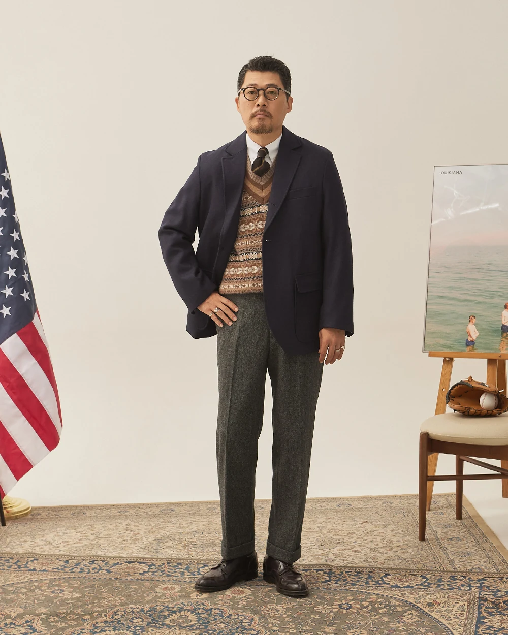 Navy gold-button blazer outfit with Fair Isle vest — single-breasted blazer over patterned Fair Isle V-neck vest, white OCBD, regimental rep tie, charcoal grey wool slacks, plaque belt, black plain-toe derbies