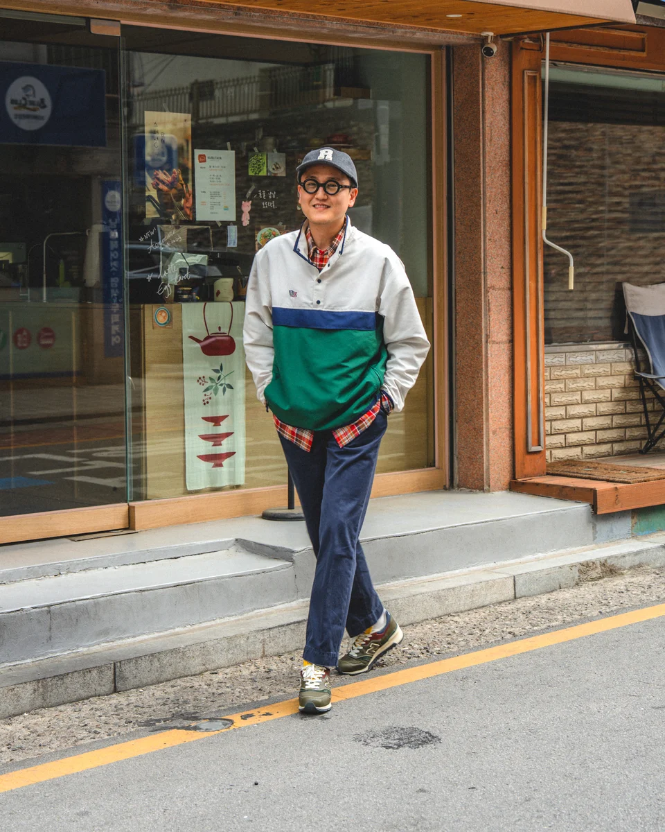 Navy chino pants outfit with anorak layered over madras shirt — street style detail