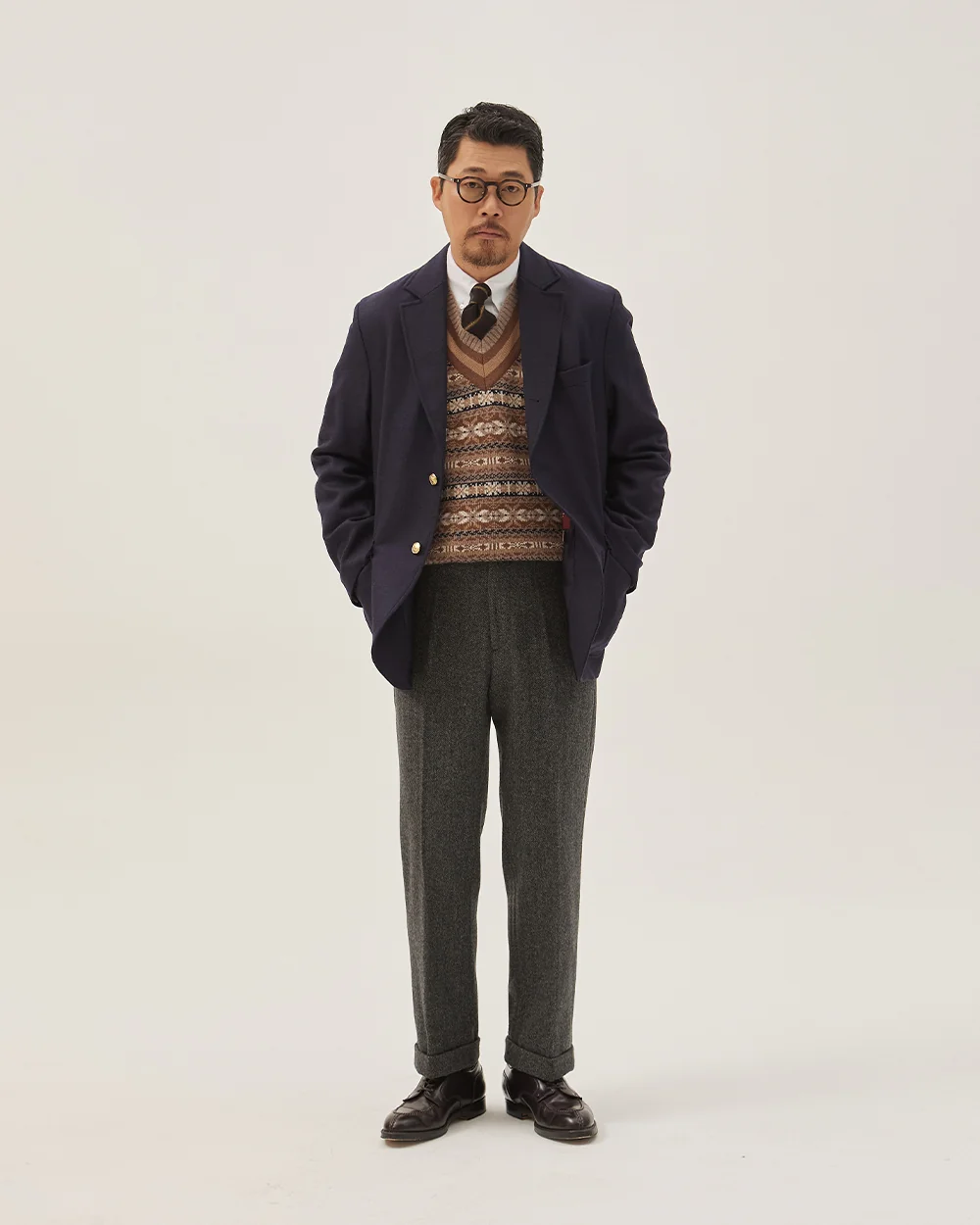 How to wear a Fair Isle vest as Ivy starter combination: navy gold-button blazer over Fair Isle vest layered with white oxford button-down and regimental rep tie, charcoal grey wool trousers, black plain-toe derbies