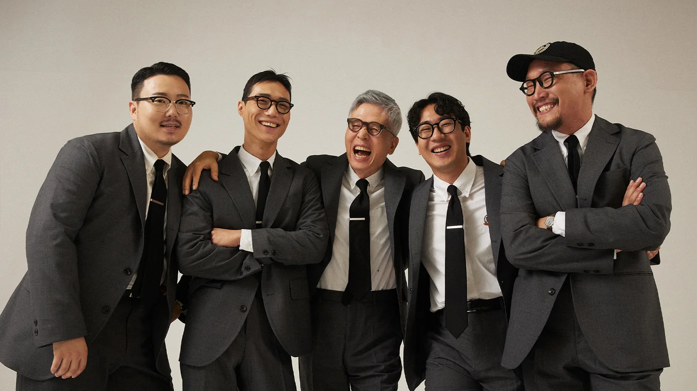 Yale Ivy style continuation — the Renacts team in grey sack suits and black ties, the direct contemporary expression of the 1902 J.Press silhouette in Seoul