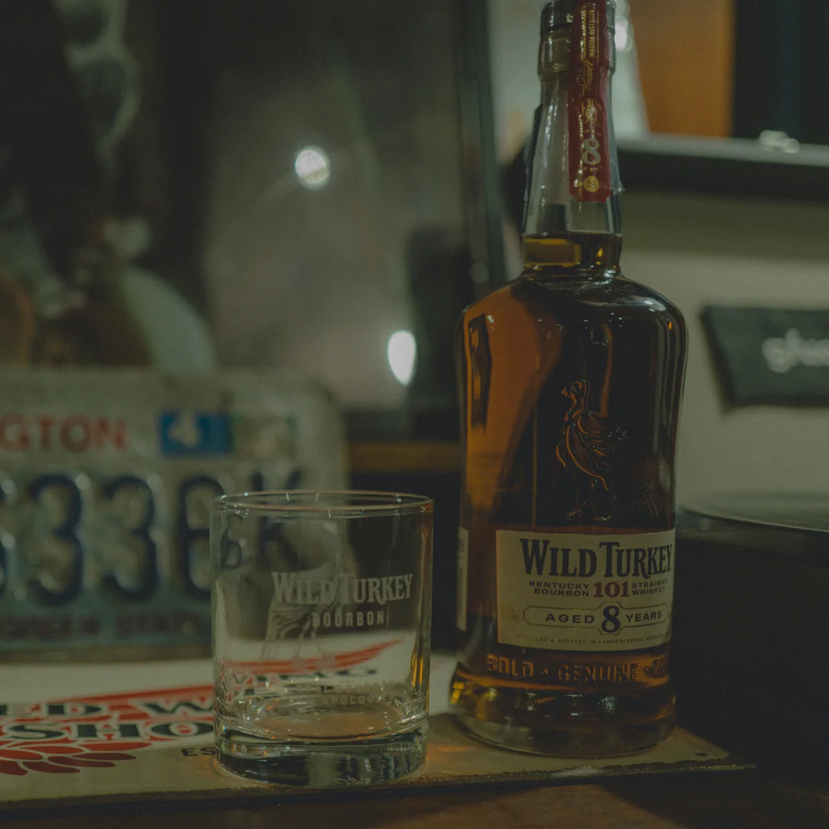 Wild Turkey 101 bottle and tasting glass beside a Kentucky license plate — Kentucky-bourbon mood