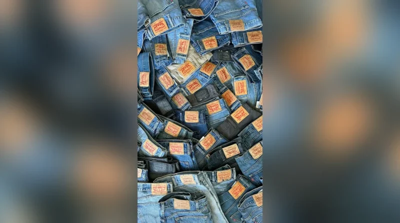 Levi 501 history thumbnail: pile of Levi's 501 jeans with red leather patches catching light, centered with blurred background — visualizing the 152-year history of the world's most reproduced denim