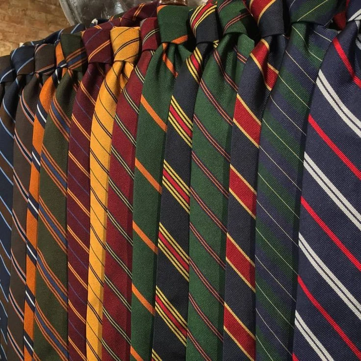 Repp tie collection close-up — diagonal stripes in multiple colors (navy, burgundy, forest green, gold, red) gathered together, showing the ribbed repp weave that defines the category beyond any one stripe pattern