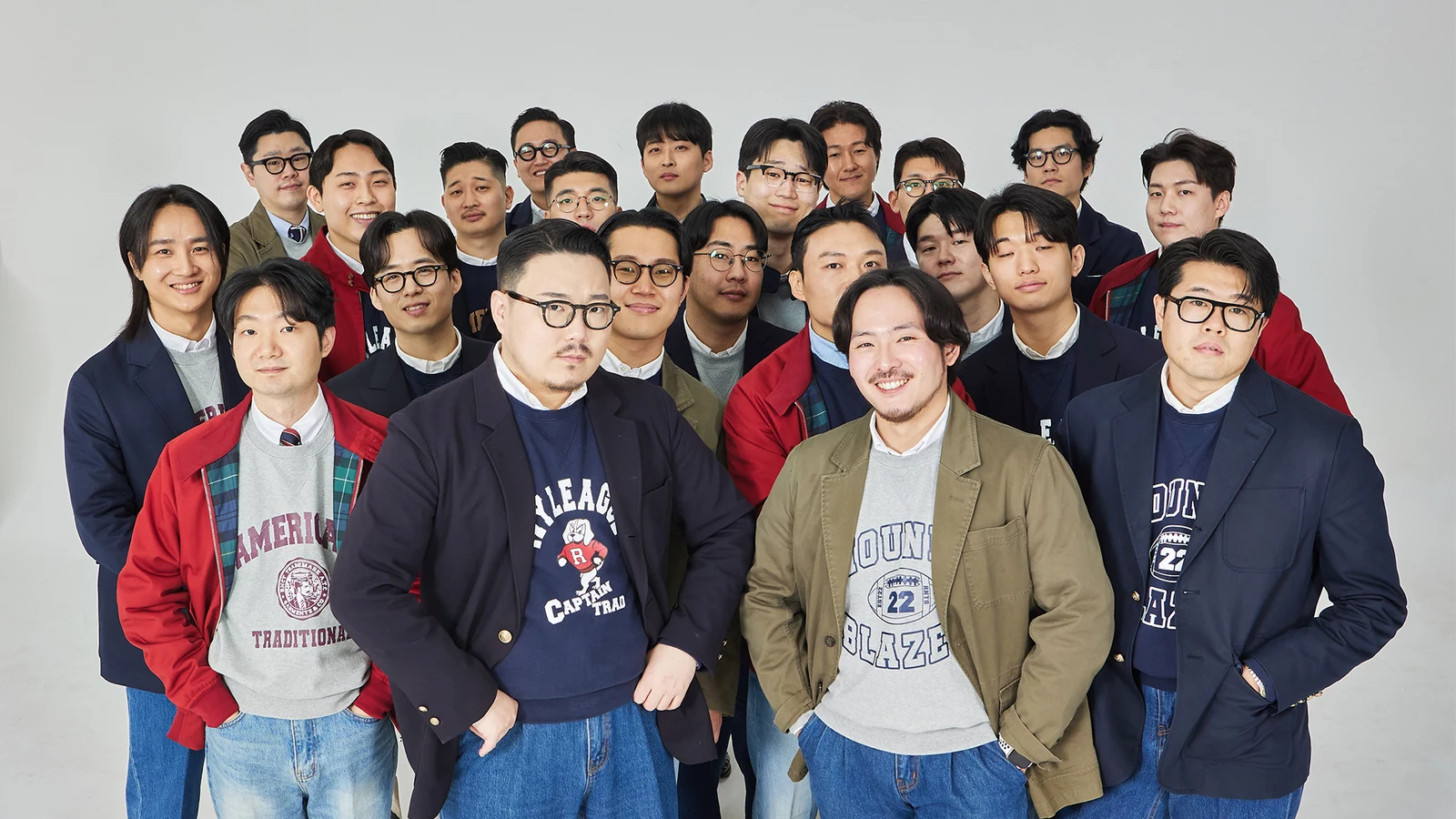 trad denim community register: full Renacts team in over twenty members, varied jackets and blazers over collegiate sweatshirts and trad denim, brand identity portrait