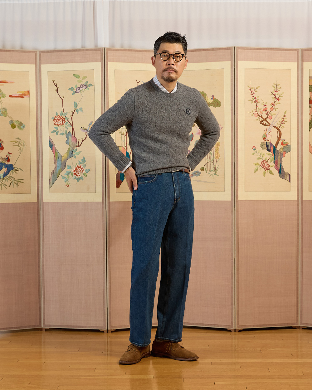 Grey cable crewneck sweater layered over an oxford shirt with the collar poking out — ivy crewneck layering