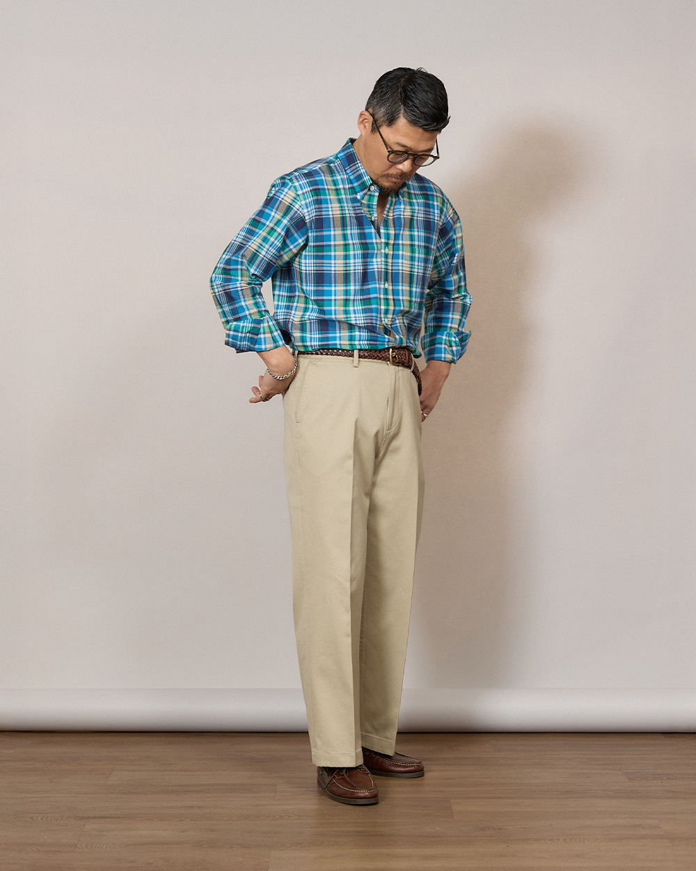 Light beige chinos worn with a blue and green madras button-down shirt tucked in and a woven leather belt, the casual end of the Ivy trouser range
