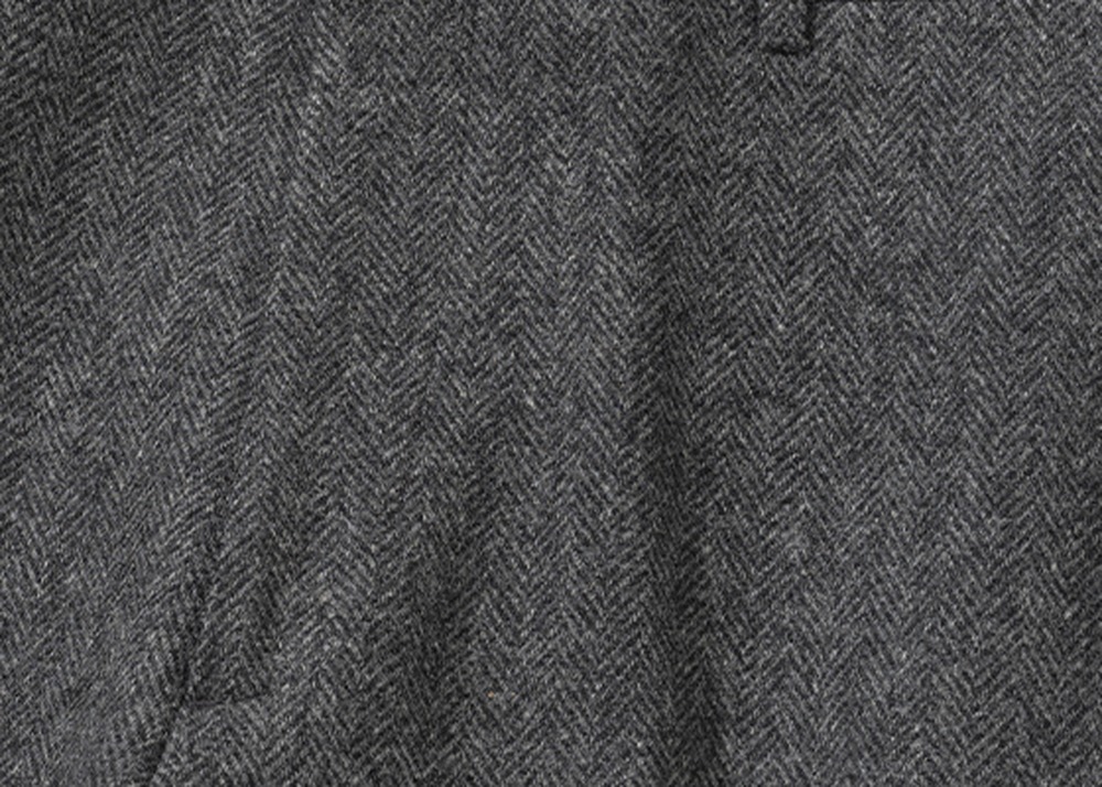 Close-up of grey herringbone tweed, showing the chevron weave and the raised surface of the cloth