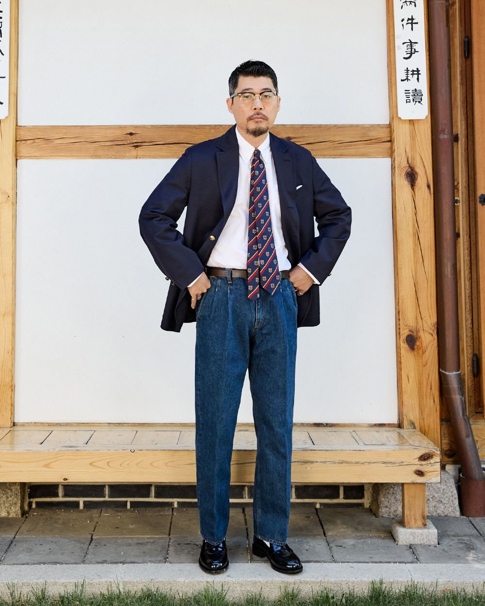 modern ivy style: navy gold-button blazer worn with a white shirt, crest repp tie and pleated wide-leg denim with cuffs, the defining modern ivy proportion