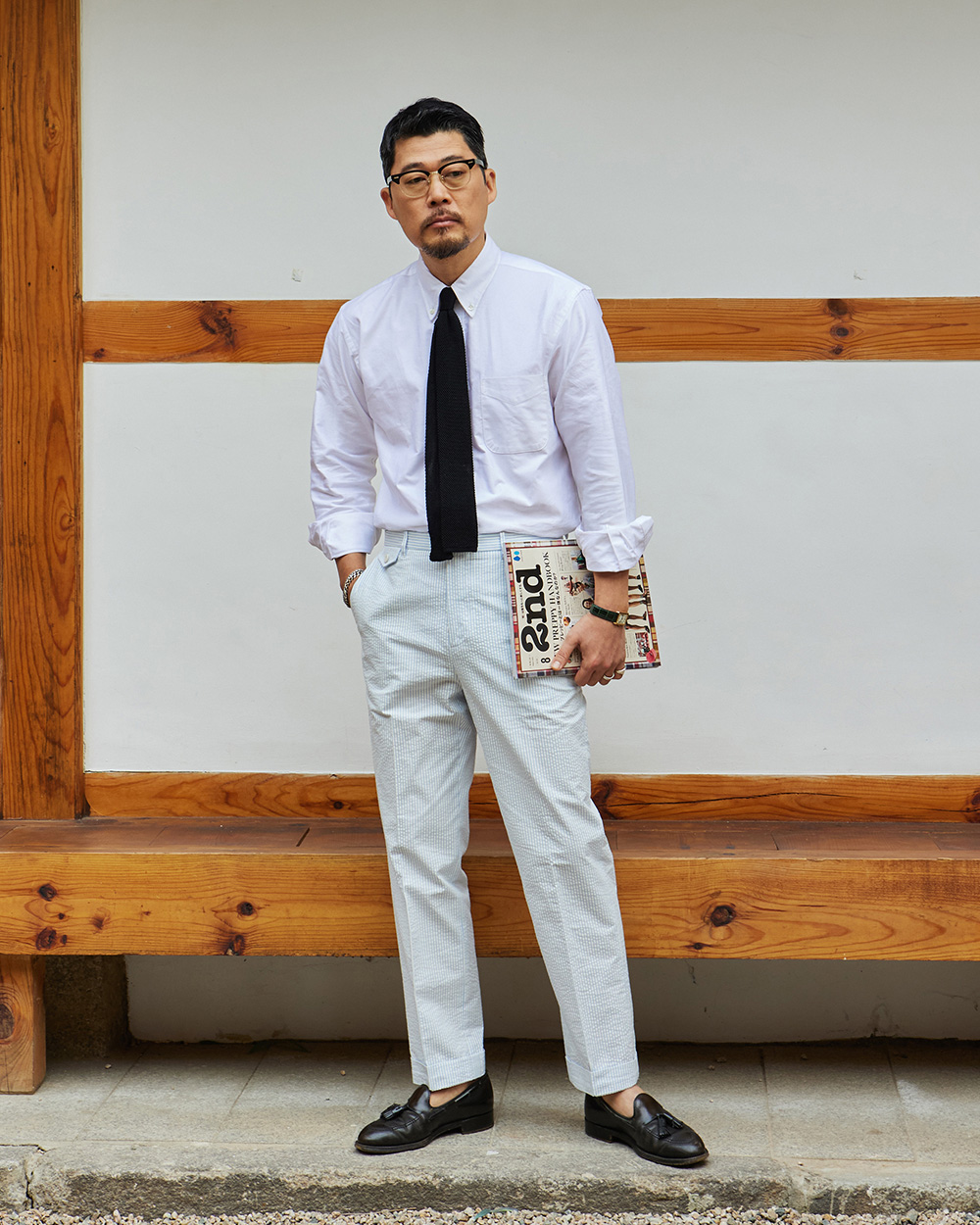 modern ivy style summer: white oxford button-down with black knit tie and high-rise pleated seersucker trousers with cuffs and tassel loafers