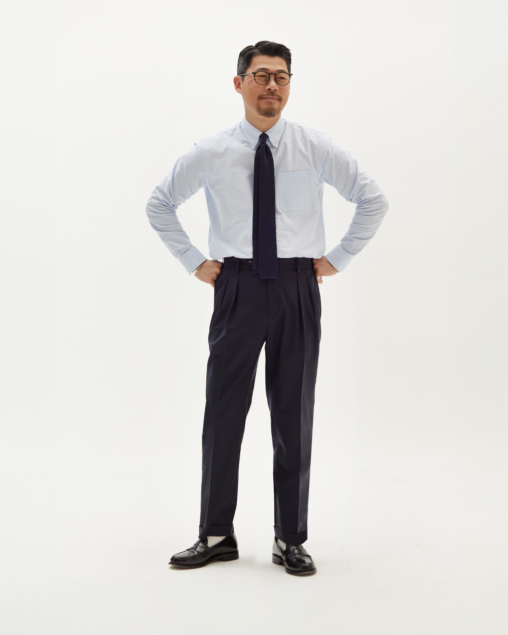 modern ivy proportions: light blue oxford button-down shirt with an unlined collar roll, navy knit tie and high-rise two-pleat wool trousers with cuffs and a full break