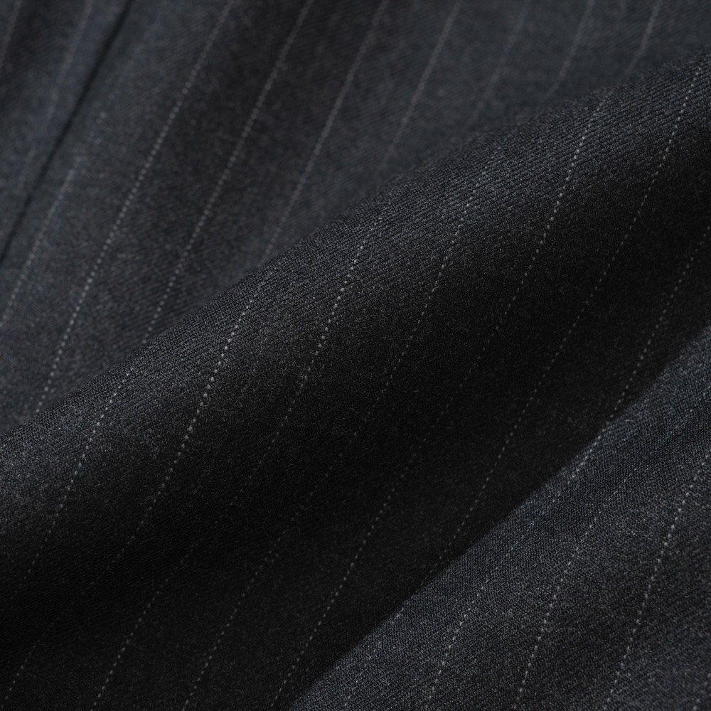Close-up of charcoal pinstripe suit cloth with fine, closely spaced light stripes on a smooth wool surface with no visible nap