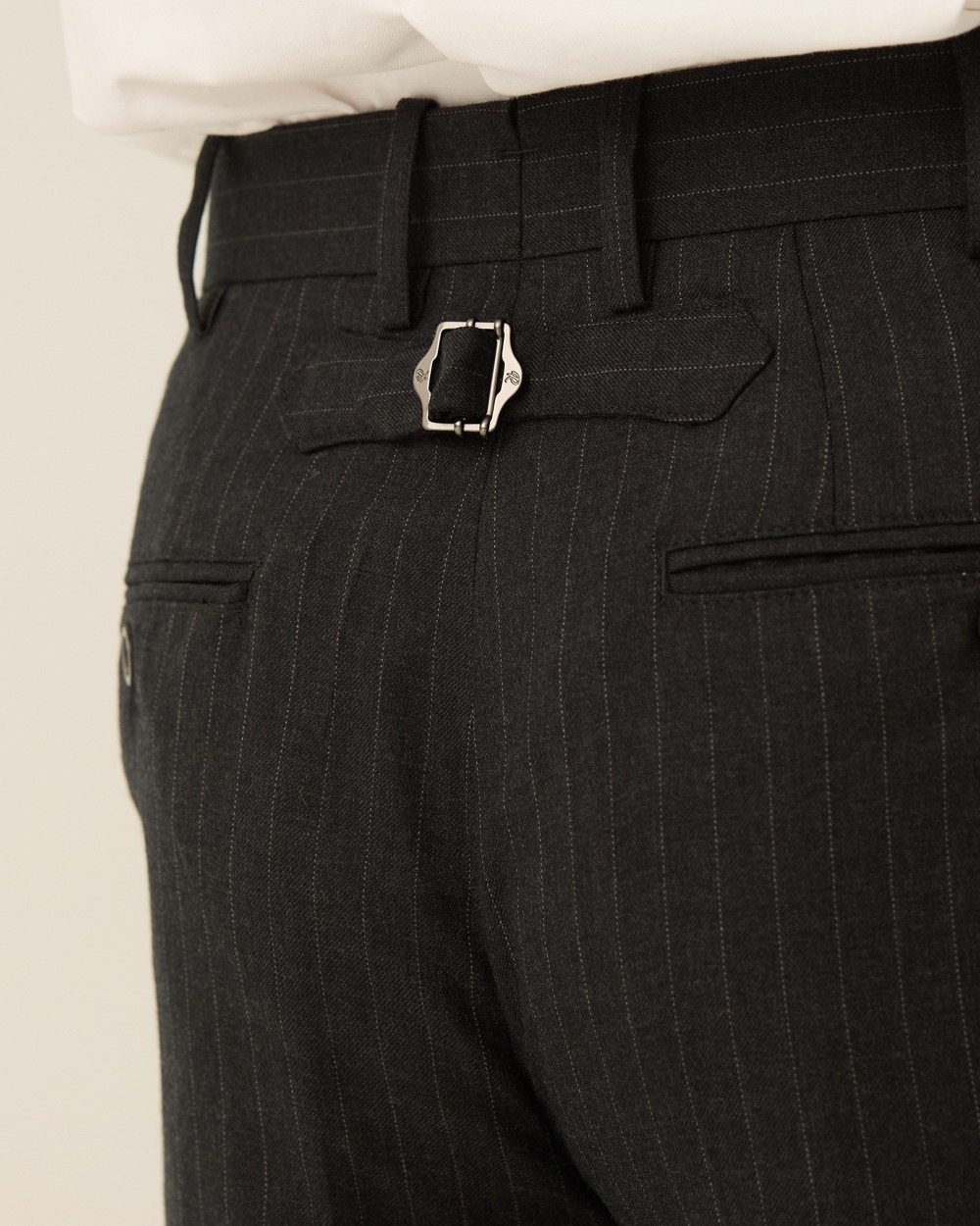 Back of charcoal pinstripe trousers worn with a tucked-in white shirt, showing the cinch-back buckle above two welt pockets