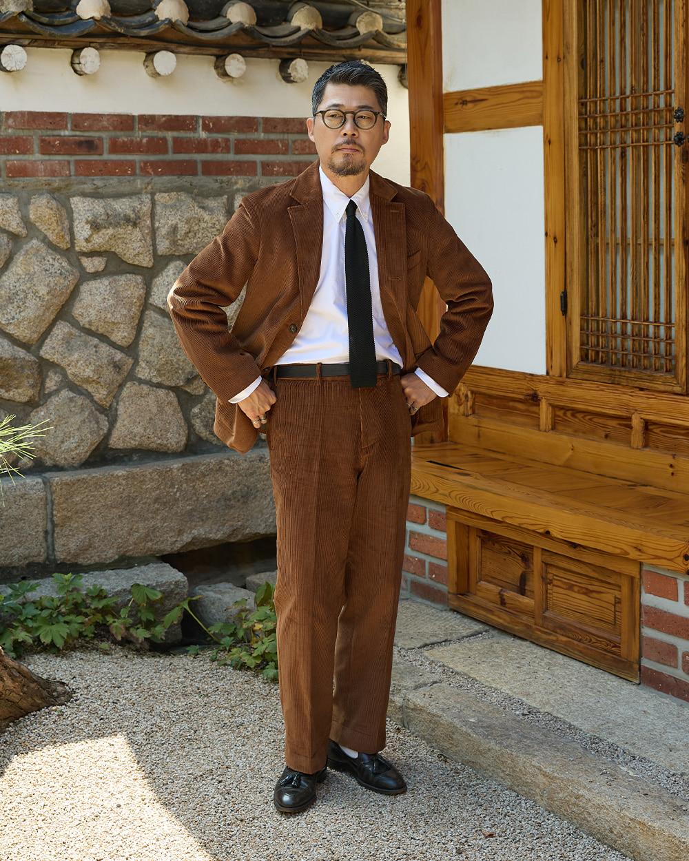 sport coat fabrics: tobacco brown corduroy sack cut blazer and matching corduroy trousers with white shirt and black knit tie, photographed at a Seoul hanok