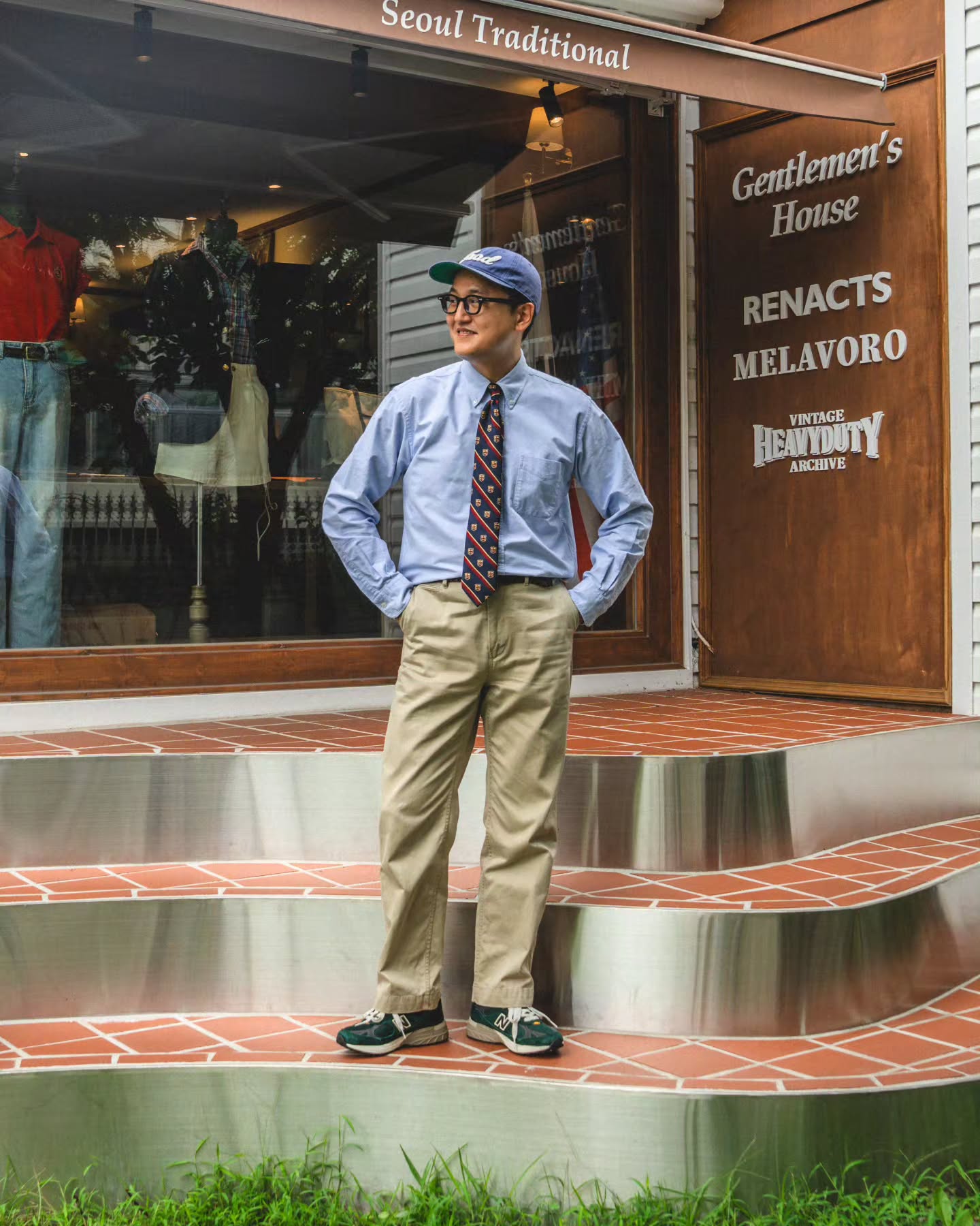 Light blue Oxford shirt and patterned tie with khaki chinos and green sneakers outside Gentlemens House.