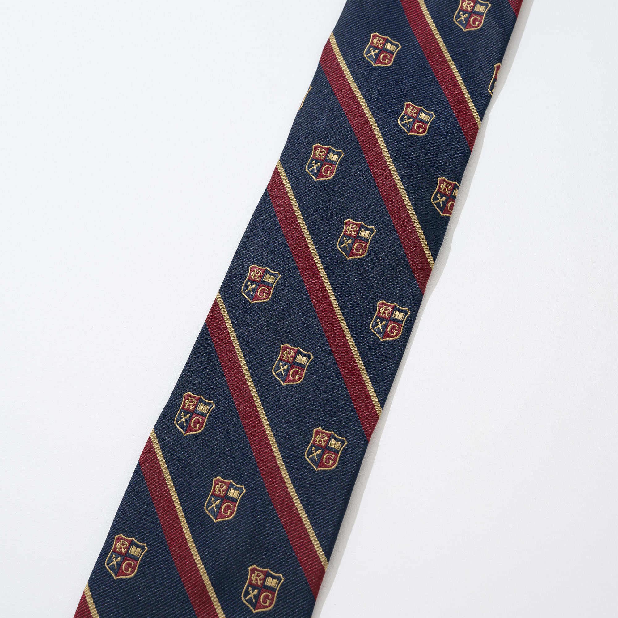 Renacts crest tie detail with red stripes and gold motifs on a navy ground.