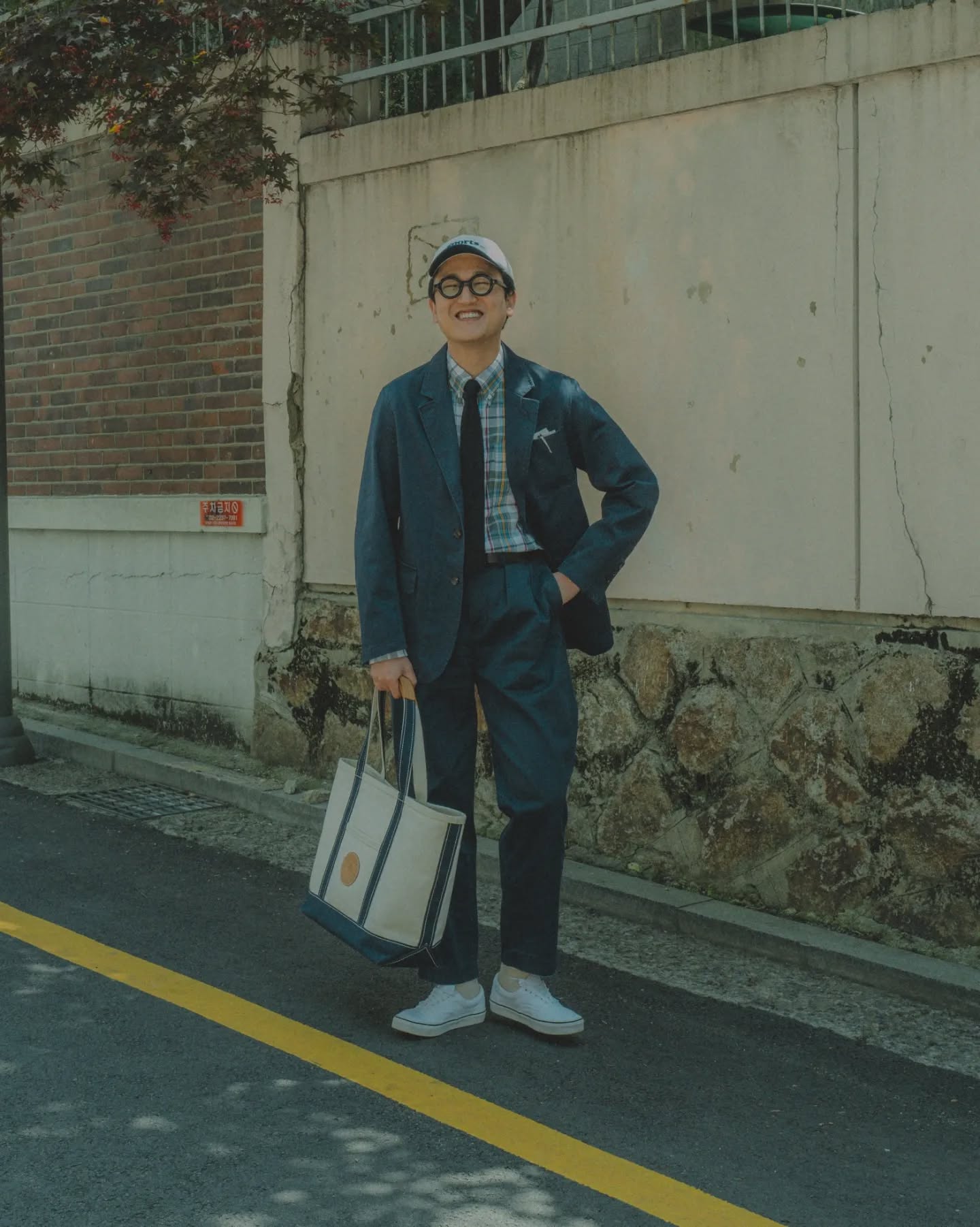 Dark blue matching jacket and trousers with a checked shirt, dark tie and low white sneakers.