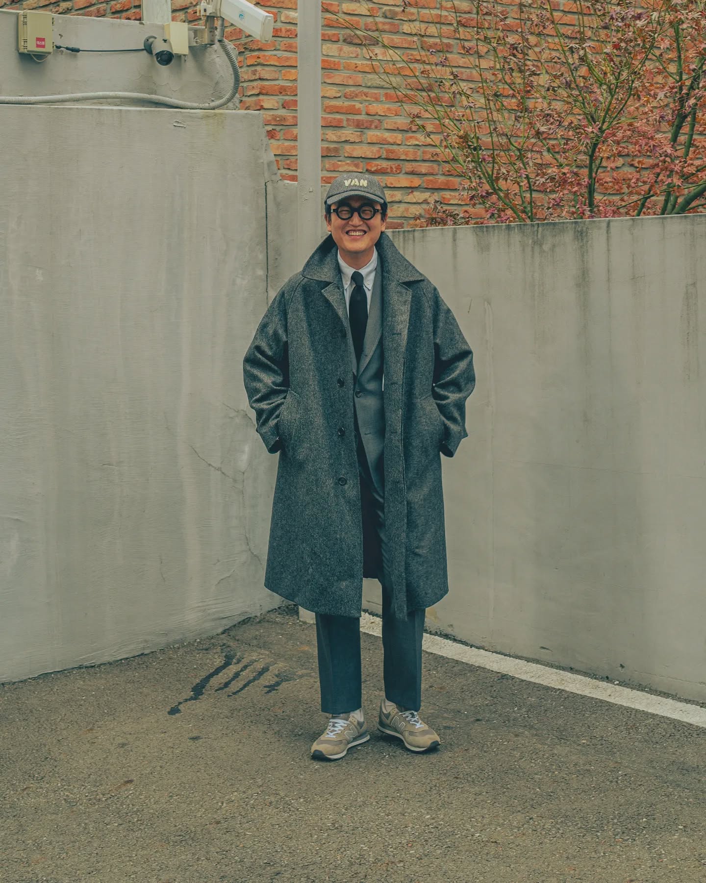 Gray coat, jacket and trousers with a dark tie and gray sneakers.
