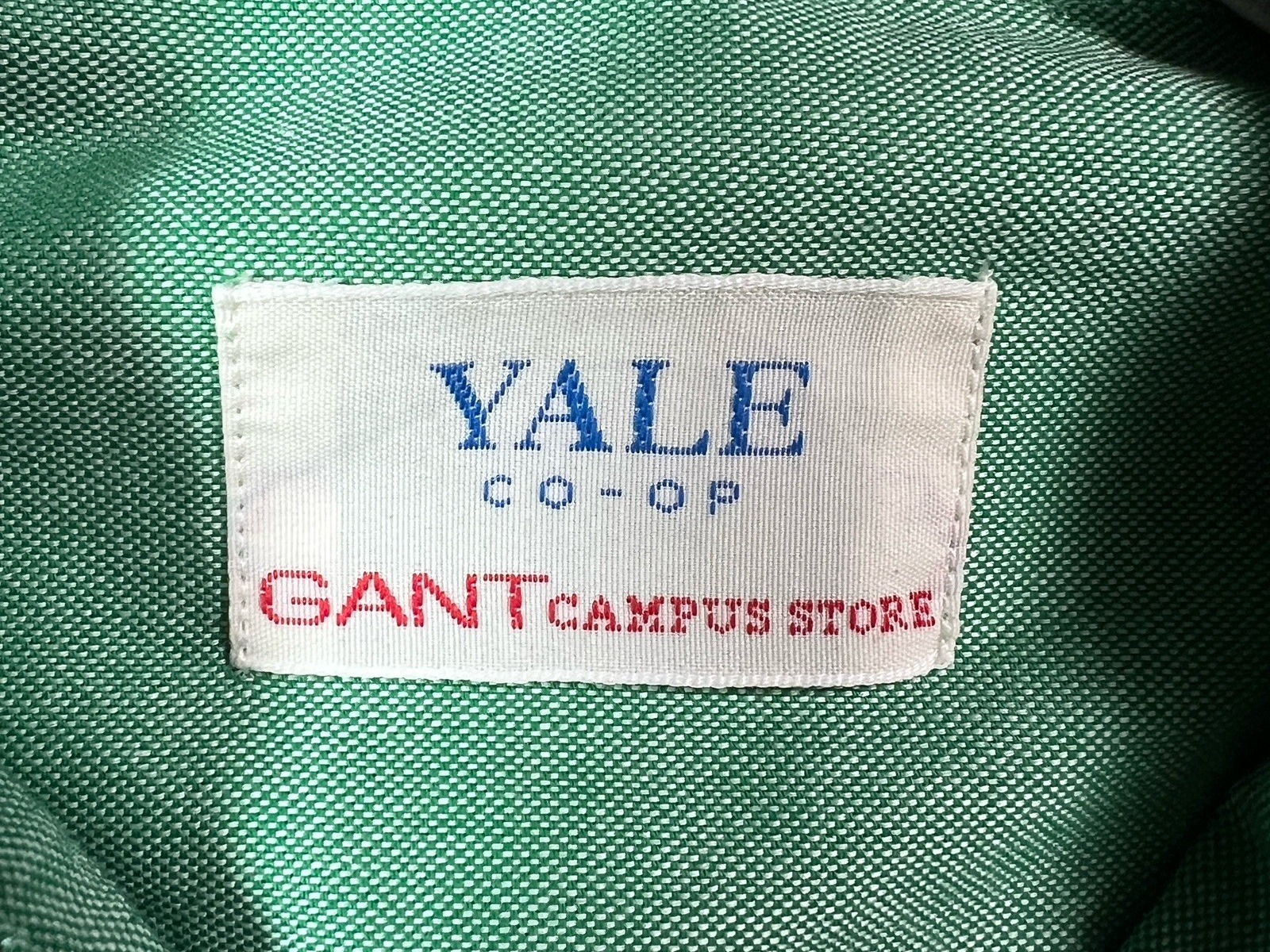 Woven label inside a green oxford cloth shirt reading YALE CO-OP in blue and GANT CAMPUS STORE in red