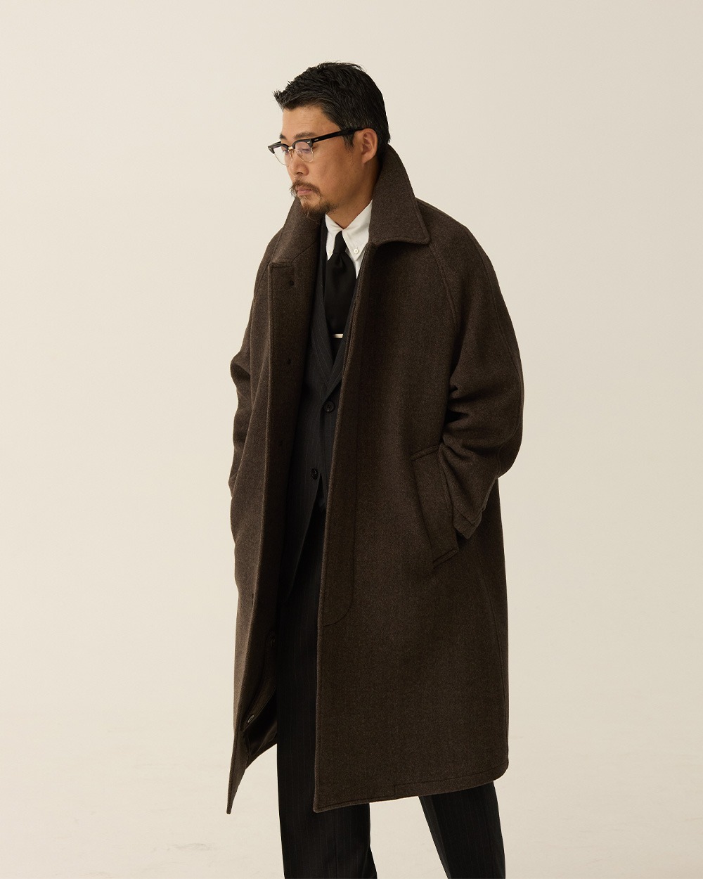 Brown herringbone Balmacaan worn open, showing the collar and front against darker inner layers.