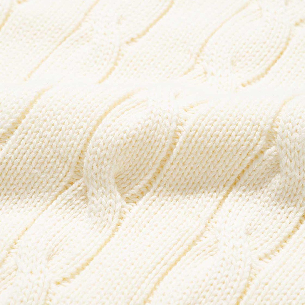 Close-up of ivory cotton cable knit with crisp, clearly defined cable columns and a smooth surface