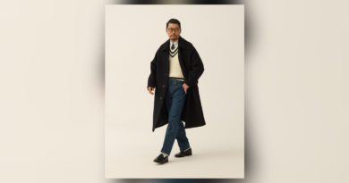 Navy Balmacaan over an ivory cricket sweater, shirt and tie, blue jeans and black loafers.