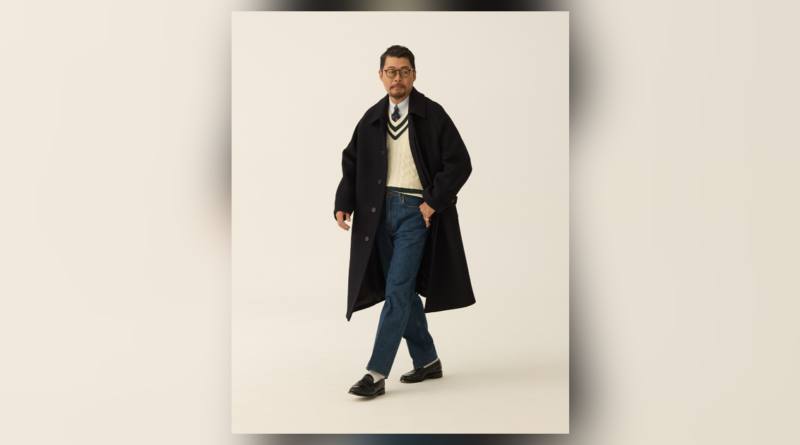 Navy Balmacaan over an ivory cricket sweater, shirt and tie, blue jeans and black loafers.