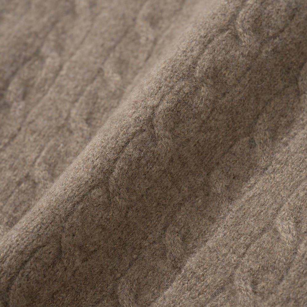 Close-up of beige merino and cashmere cable knit with a soft, slightly fuzzy surface over the cable columns