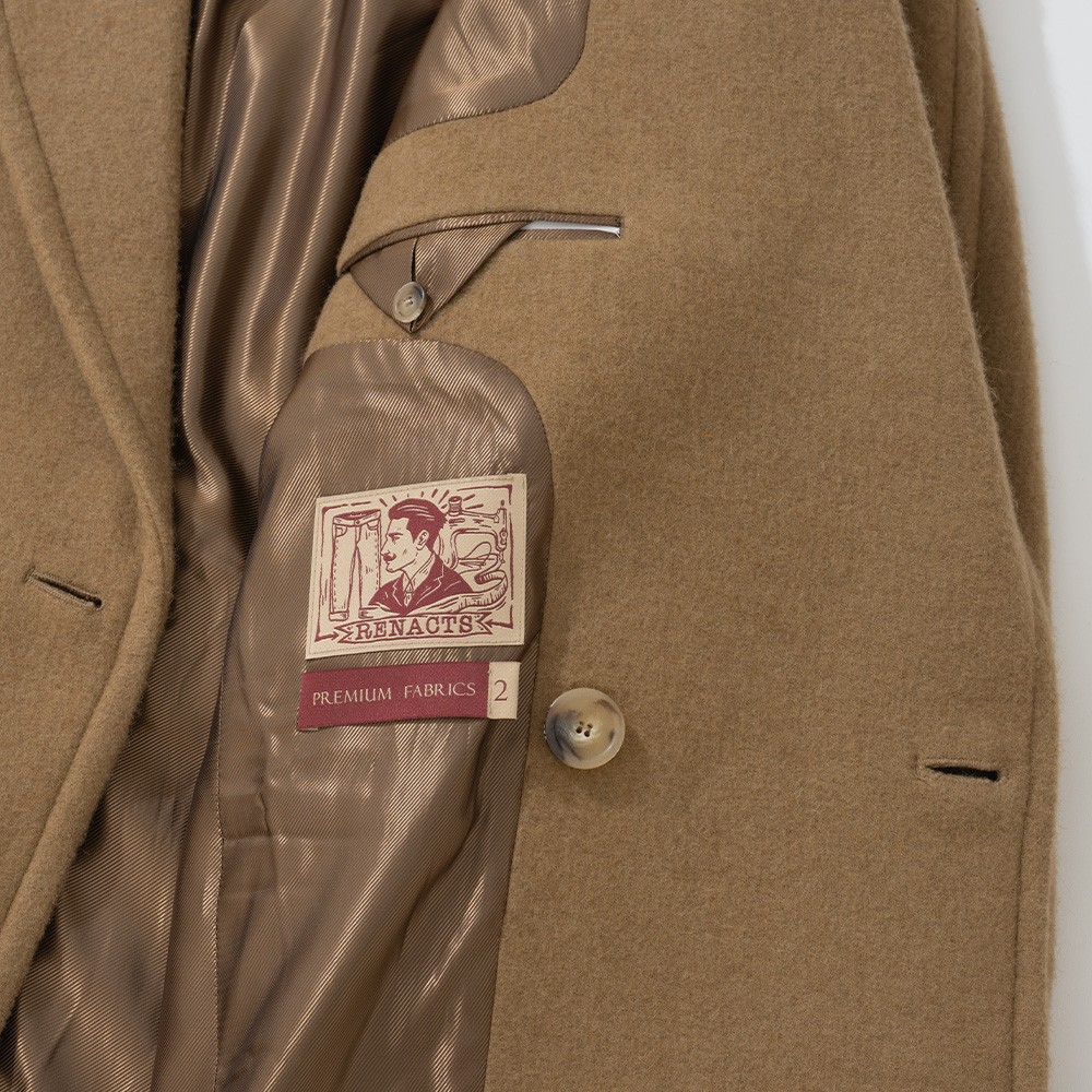 Inside of a camel polo coat showing the light brown lining, a woven label and a horn button